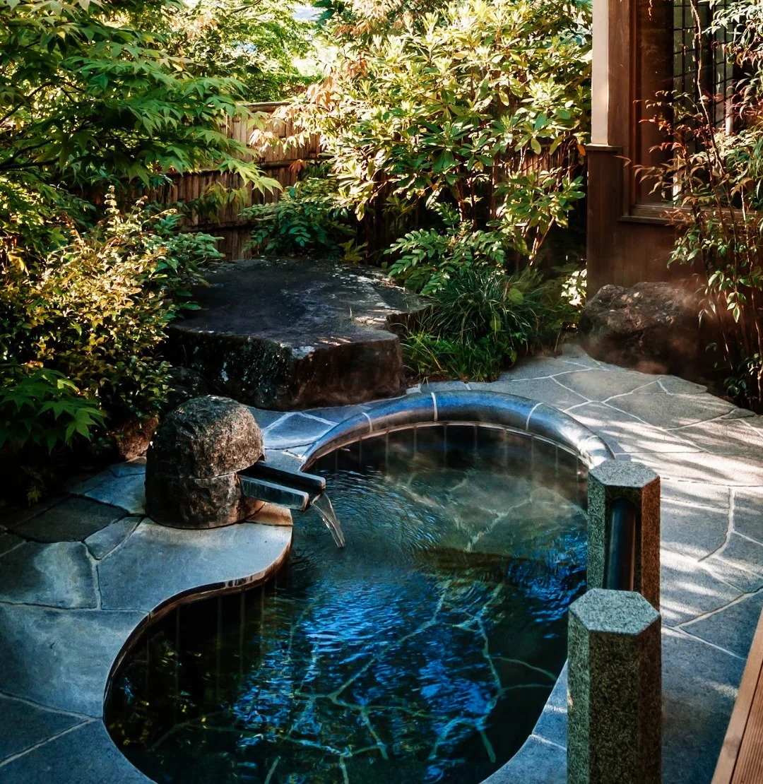 A private stone onsen bath in a leafy garden