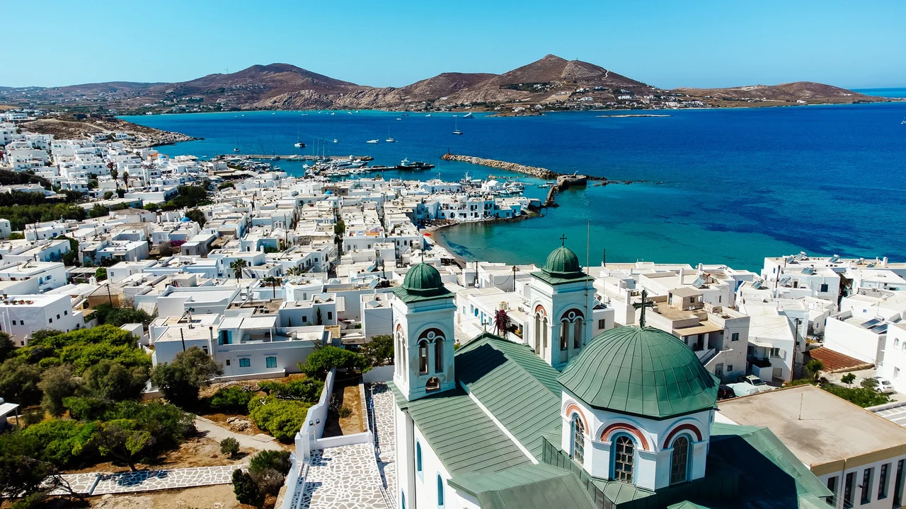 Whitewashed houses and a green-domed church above a blue harbor