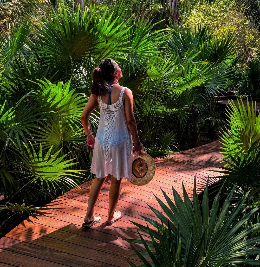 Walking a sunlit boardwalk through the palms at Naviva